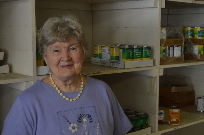 Marcella Ramsbacher stands beside the canned goods at Helping Hands in Edna,